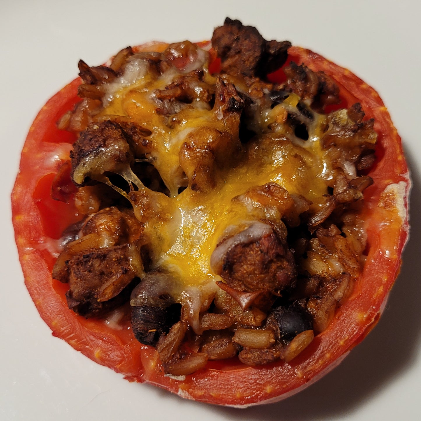 Half a red ripe round Pera Tipo Cosentino Tomato, stuffed, baked, and topped with melted cheese