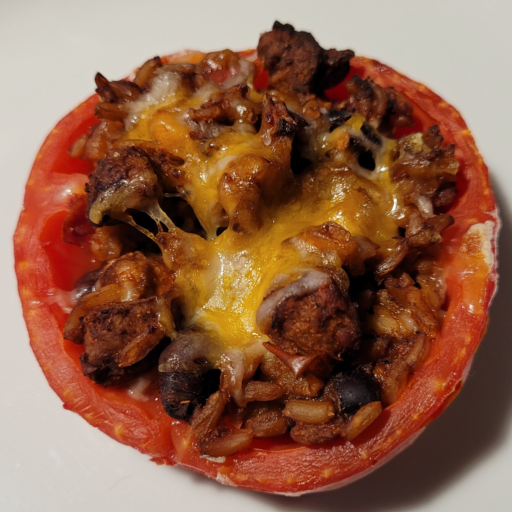 Half a red ripe round Pera Tipo Cosentino Tomato, stuffed, baked, and topped with melted cheese